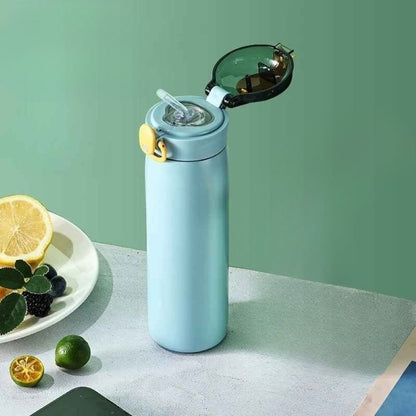 Gourde isotherme Lagune 460 ml avec paille intégrée posée sur une table avec des fruits