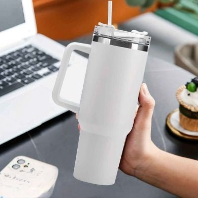 Bouteille isotherme Flex 1.2 L/1200 ml – Pratique et durable pour sport -une main tient bouteille blanche pres d'ordinateur Soiflex